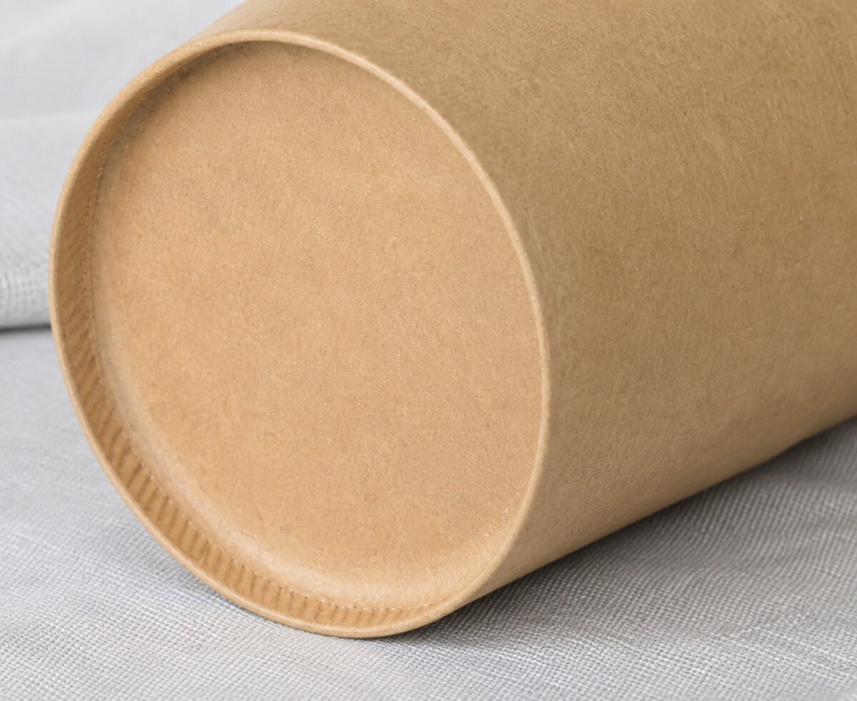 Kraft food-container bottom with a shallow recessed disk and crimped edge on gray linen