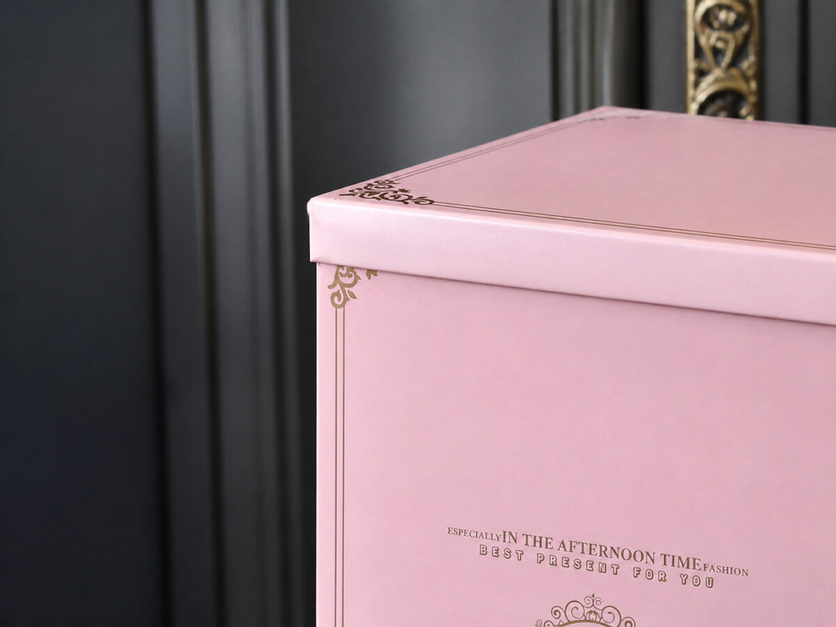 Close-up of a pink cake box lid and gold decorative corner border