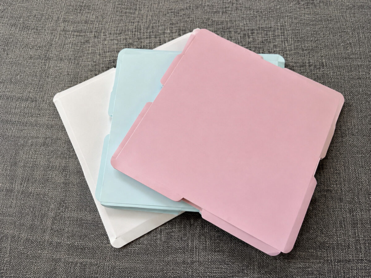 Pink mint and white flat paper cake box components on gray fabric
