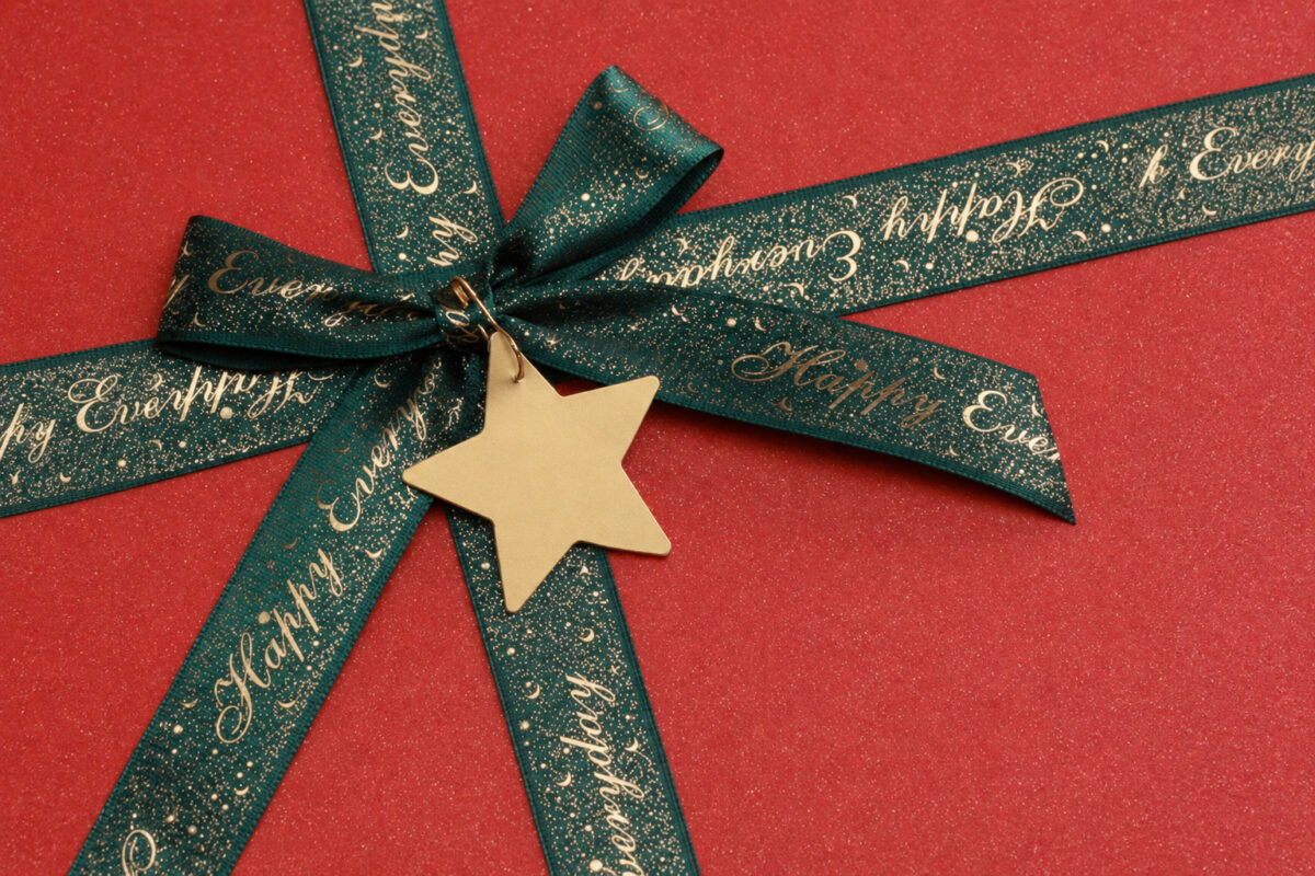 Close-up of a green Happy Everyday ribbon and flat gold star tag on a red gift box