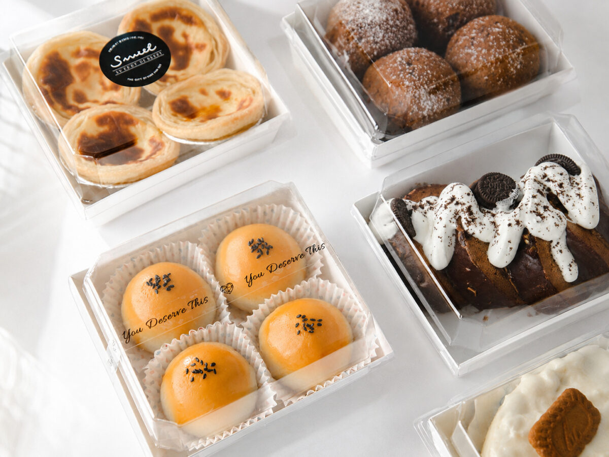Clear-lid white bakery trays with custard tarts, sesame buns and cream pastries