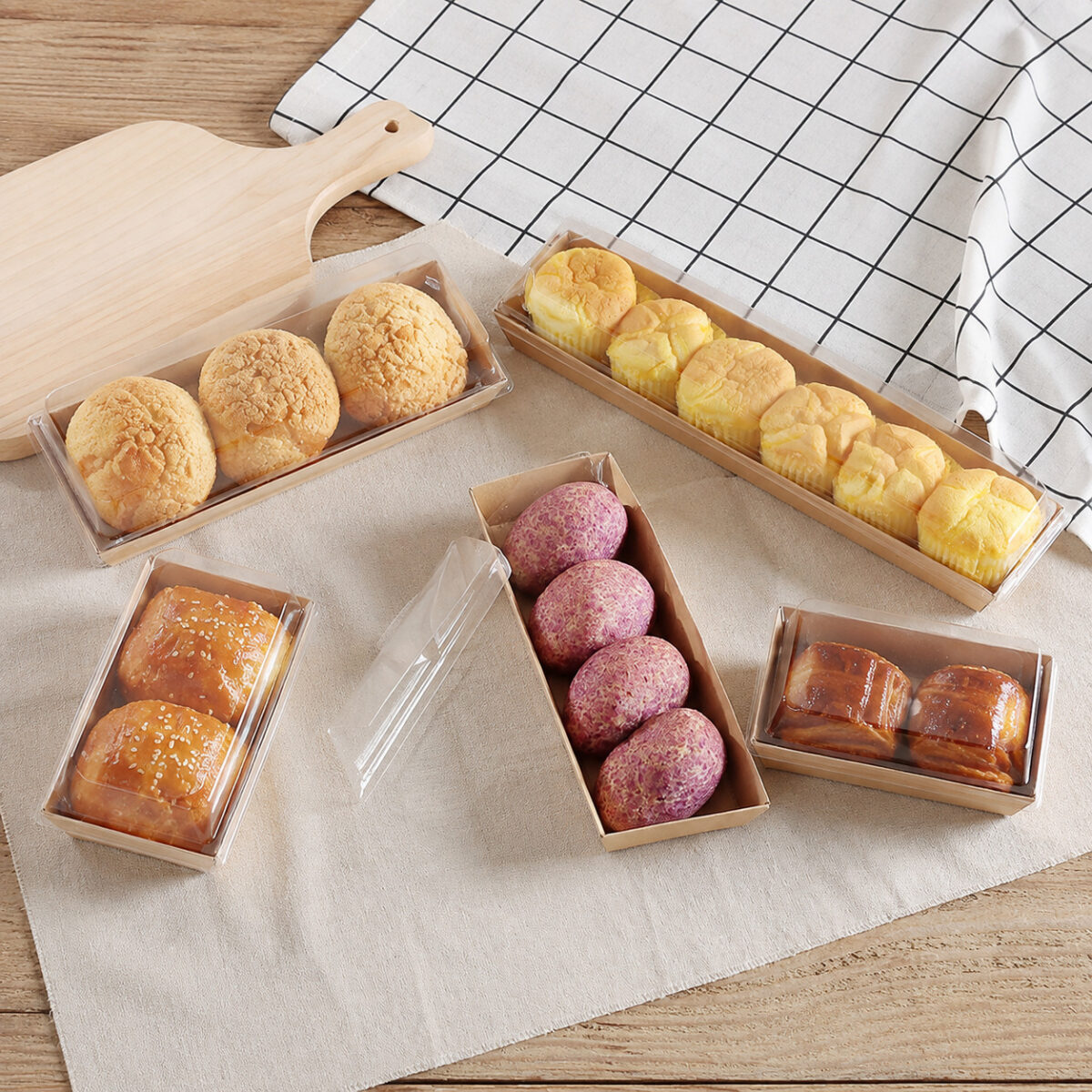 Kraft pastry trays with clear covers holding muffins choux buns and purple pastries
