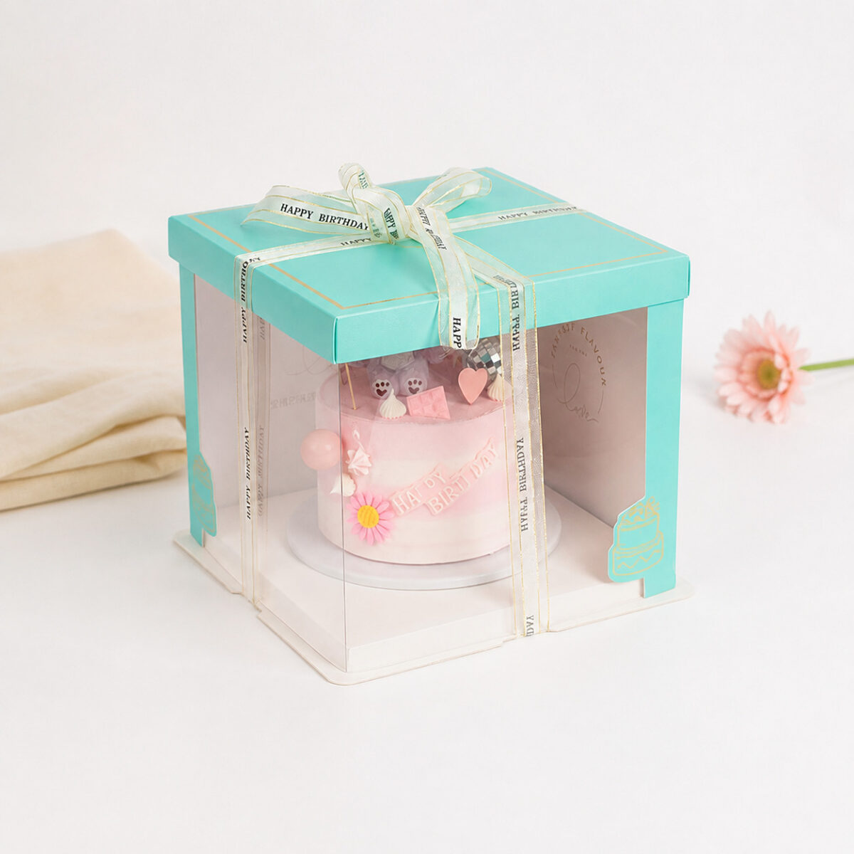 Turquoise Frame Cake Boxes with Clear Panels Turquoise clear-panel cake box with a pink birthday cake and cream Happy Birthday ribbon