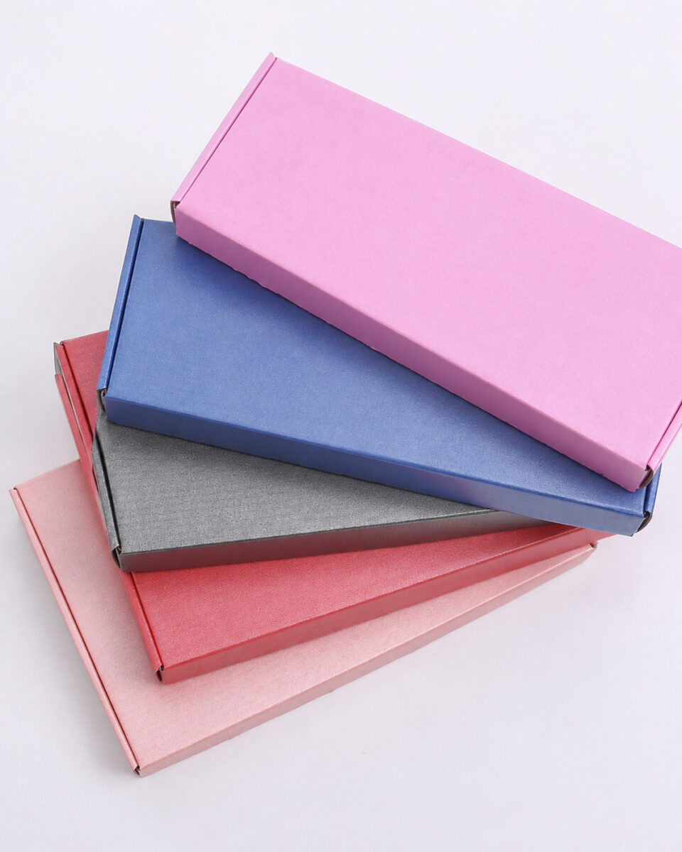 Five flat folding gift boxes in pink, blue, grey, red and rose arranged in a fan