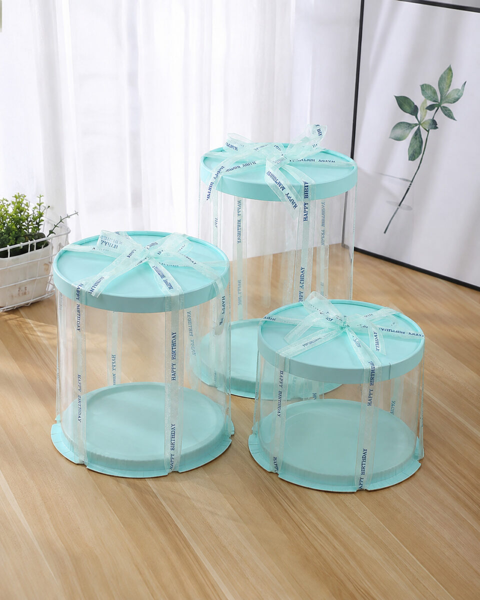 Three empty mint round cake boxes with clear walls and Happy Birthday ribbon