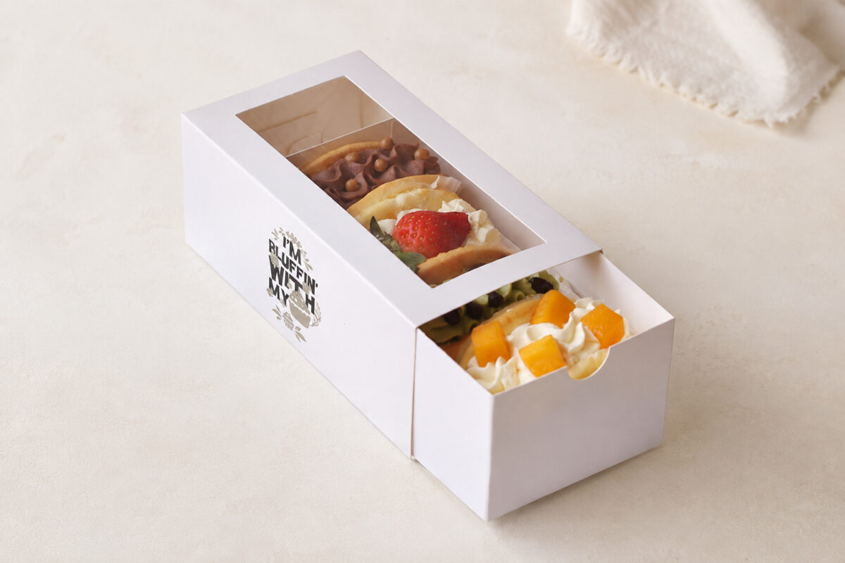 White drawer dessert box with a clear top window and four assorted pastries