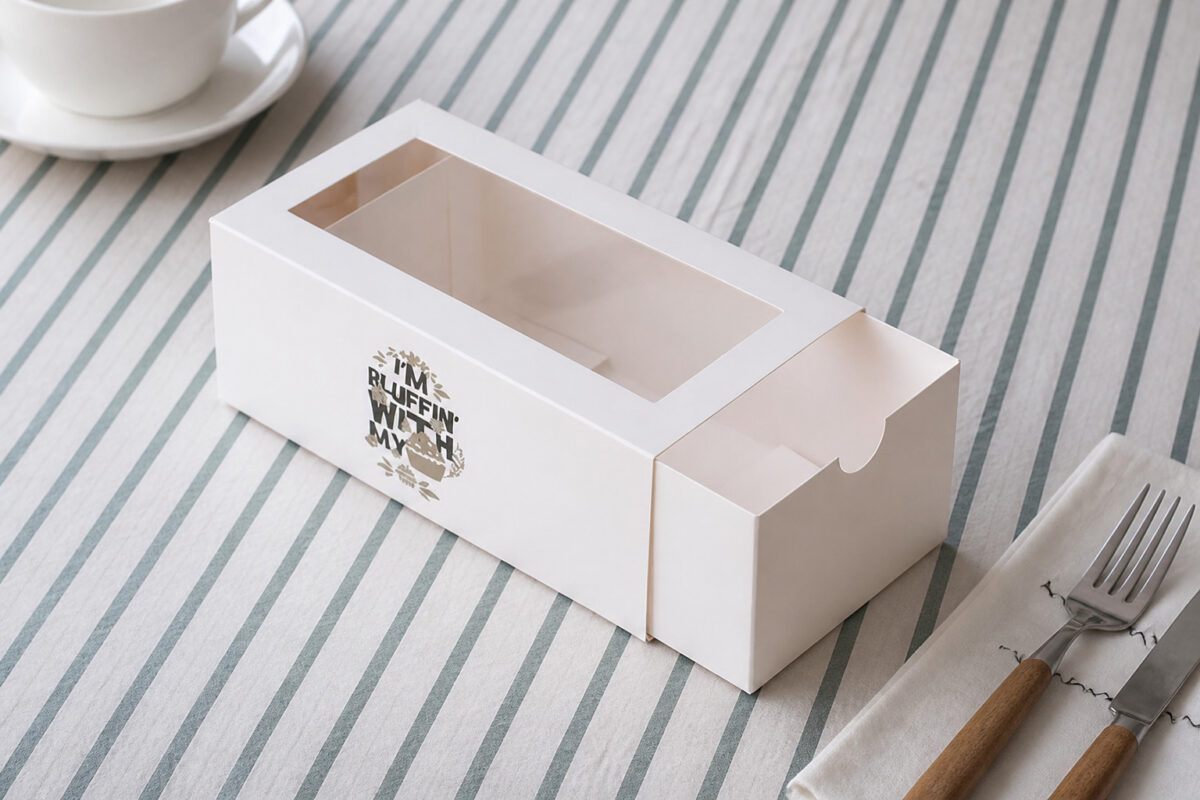 Empty white drawer dessert box with a clear window on a striped cloth