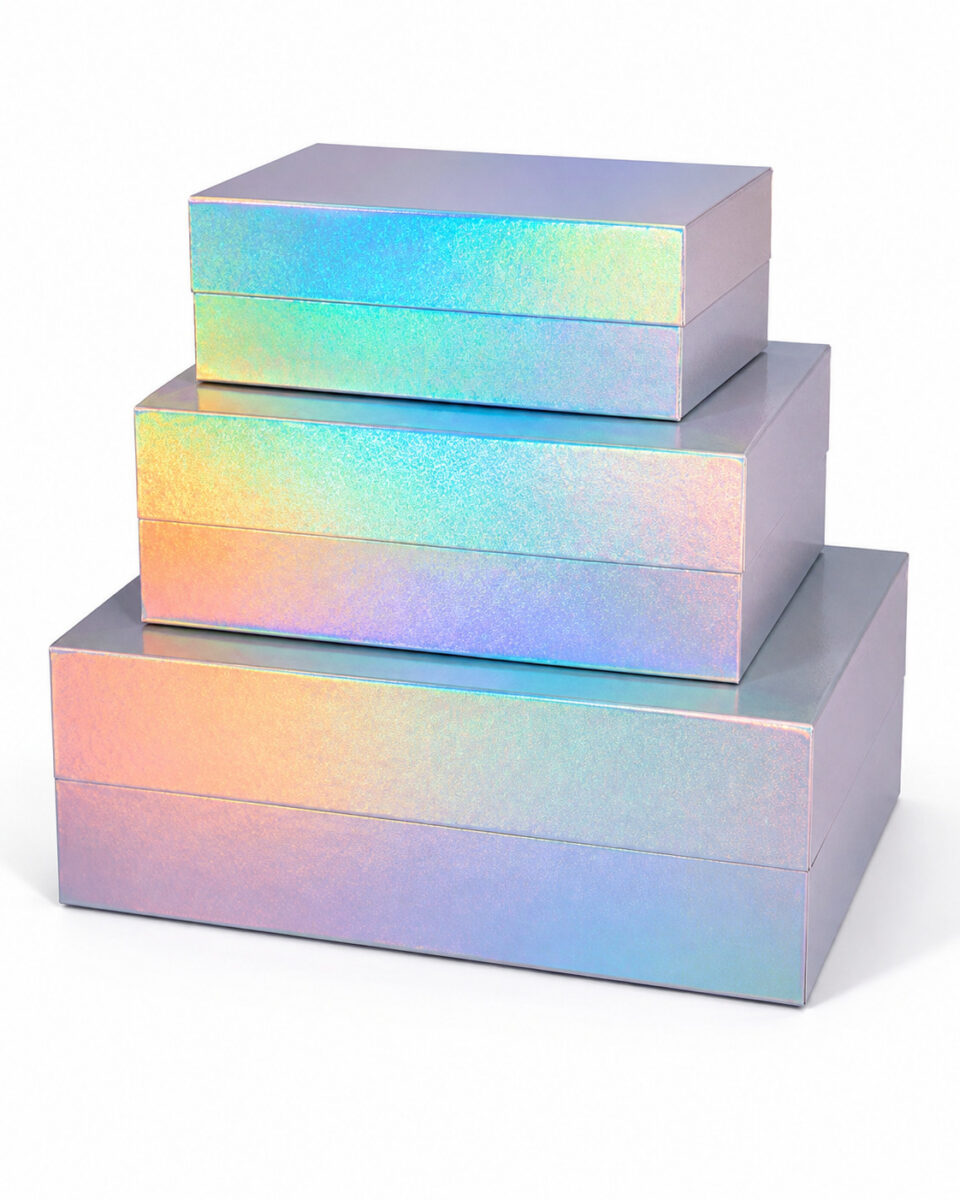 Three sizes of closed iridescent rectangular gift boxes stacked on a white surface