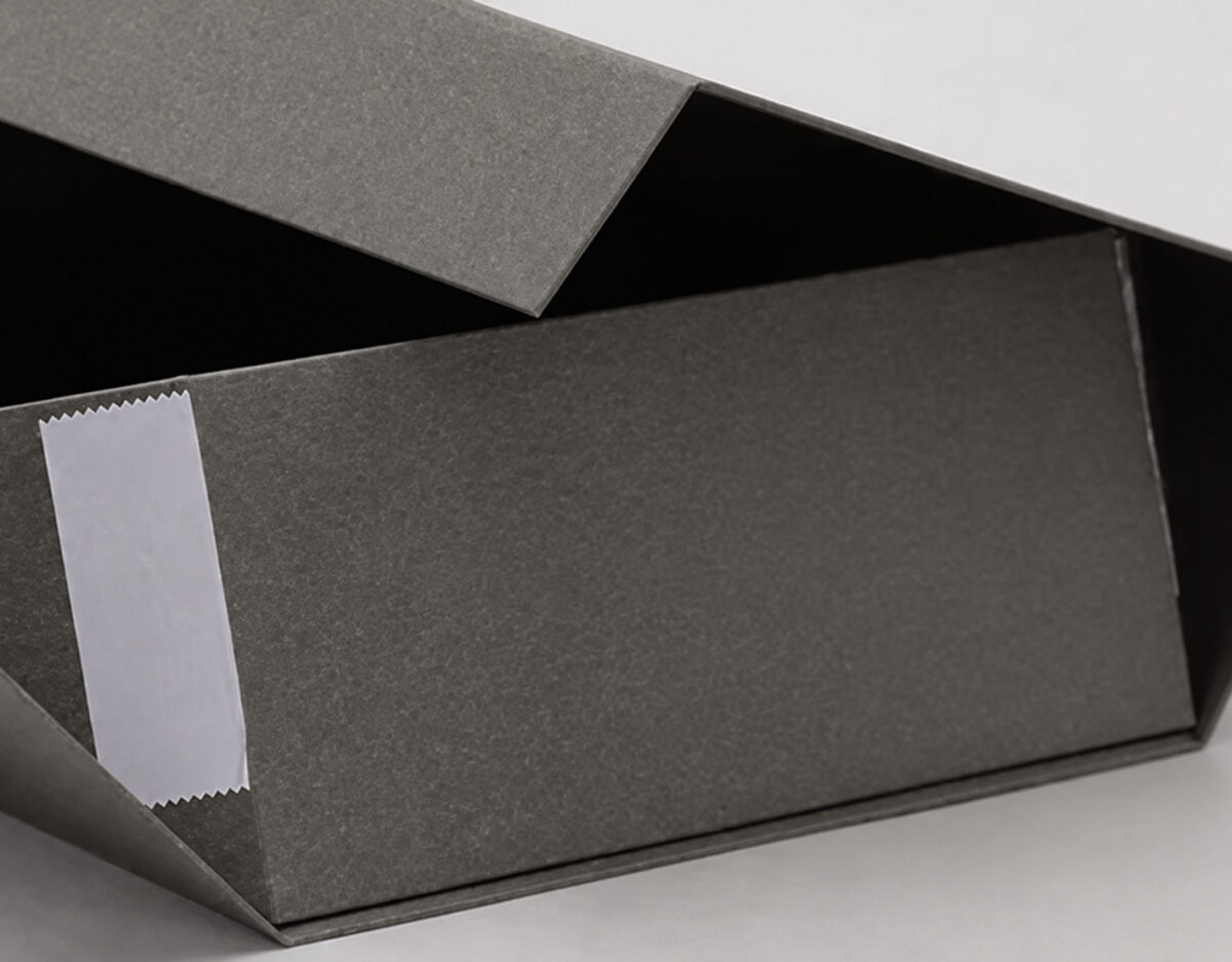 Close-up of a charcoal folding gift box corner and white adhesive liner