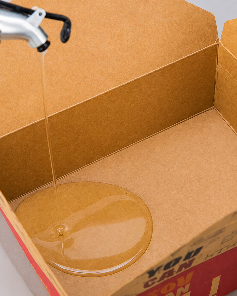 Oil being poured into an open kraft food carton for a visual demonstration