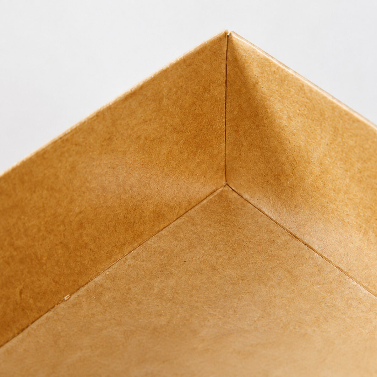 Close-up of the folded inside corner and paper seams of a kraft cake roll tray