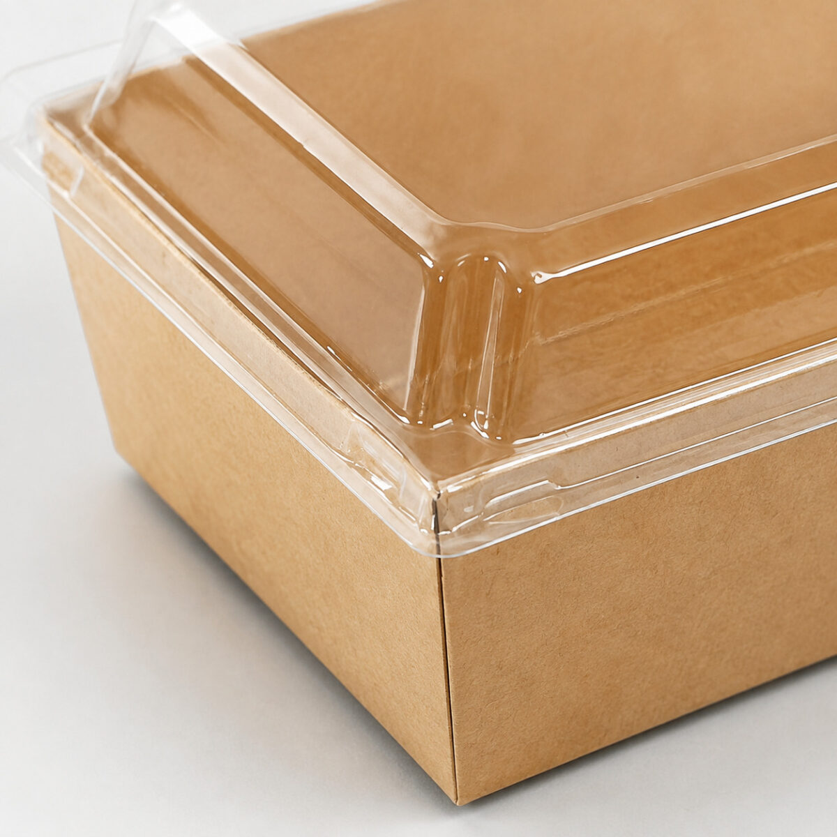 Close-up of a clear fitted lid corner and locking rim on a kraft dessert tray