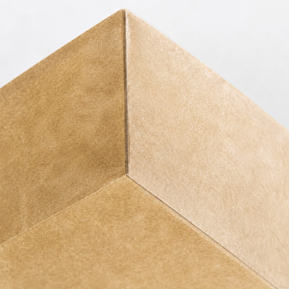 Inside corner seam and paper texture of a light kraft cake roll tray