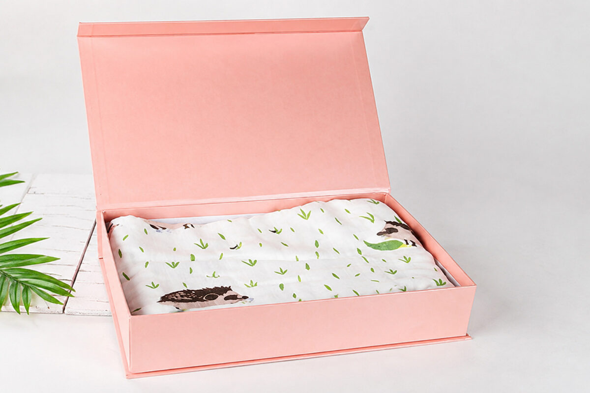 Open peach folding gift box containing a folded hedgehog-patterned cloth