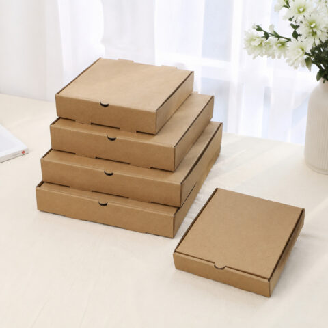 Five plain brown kraft pizza boxes in graduated sizes on a light tabletop