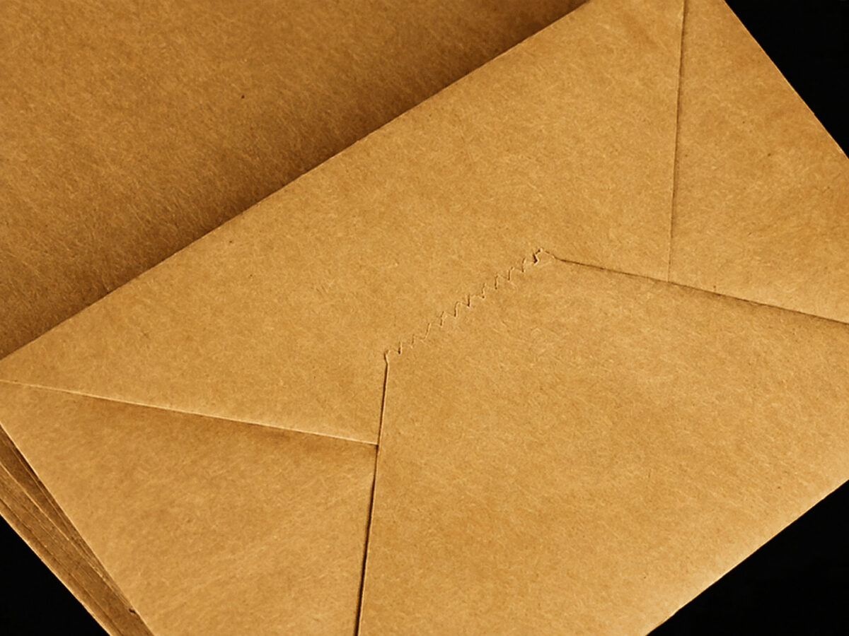 Kraft paper bag bottom showing overlapping triangular flaps and a cut paper edge