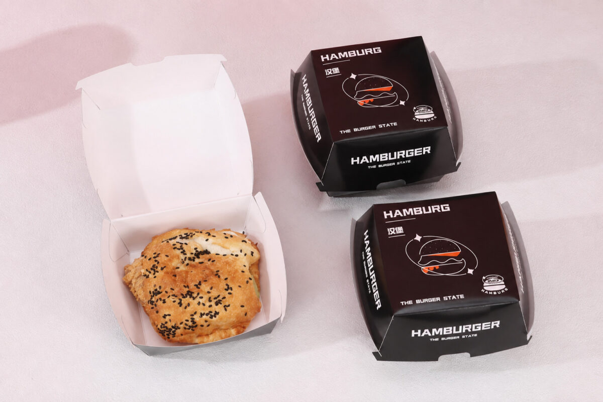 Two printed burger cartons beside an open carton holding a sesame chicken burger