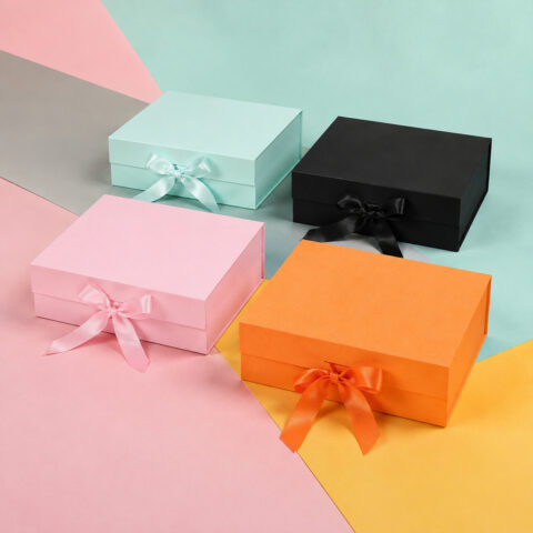 Pink mint black and orange ribbon gift boxes arranged on colored paper backgrounds