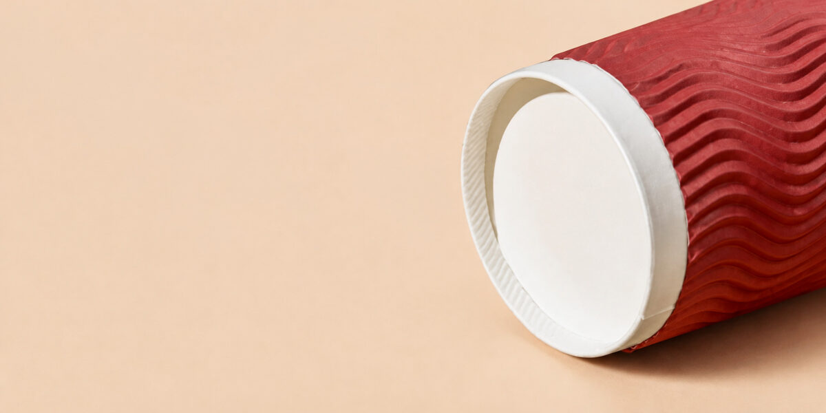 Recessed white base and crimped foot ring of a red ripple wall coffee cup