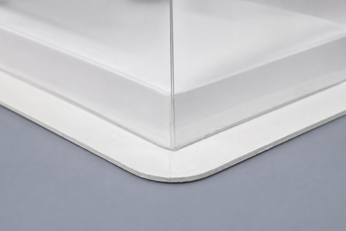 Close-up of a clear square cake cover corner on a white paper base