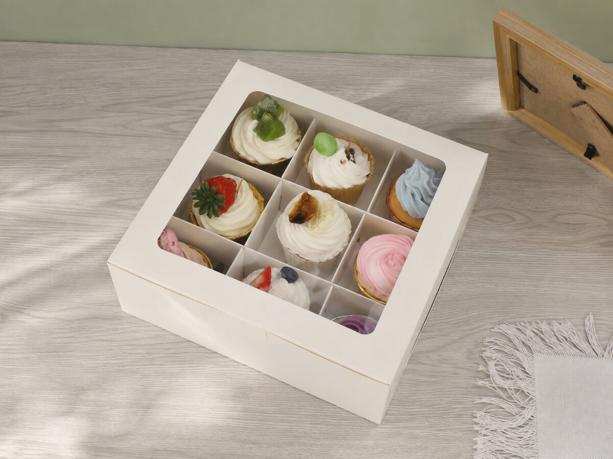 White nine-compartment cupcake box with a large clear window on a gray wood table