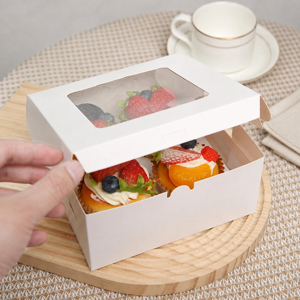 White dessert carton with a raised rectangular window lid and two fruit-topped cakes