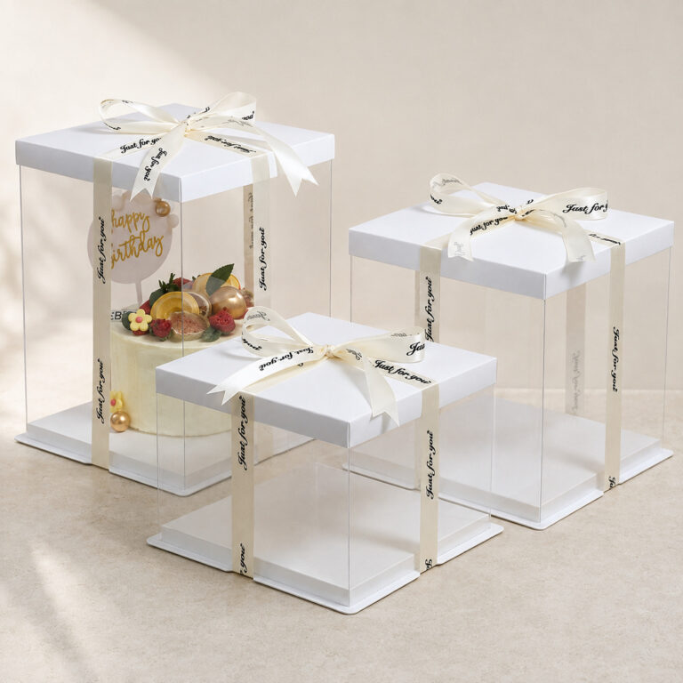 Three clear square cake boxes with white lids and ivory ribbons, shown in tall, medium and low heights