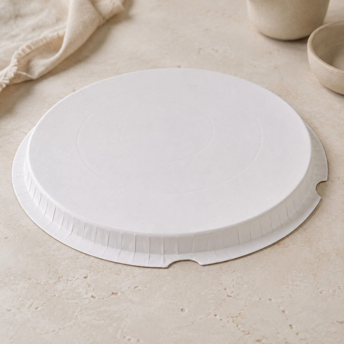 White round cake-box base detail showing the raised platform, downward crimped edge and notched outer flange