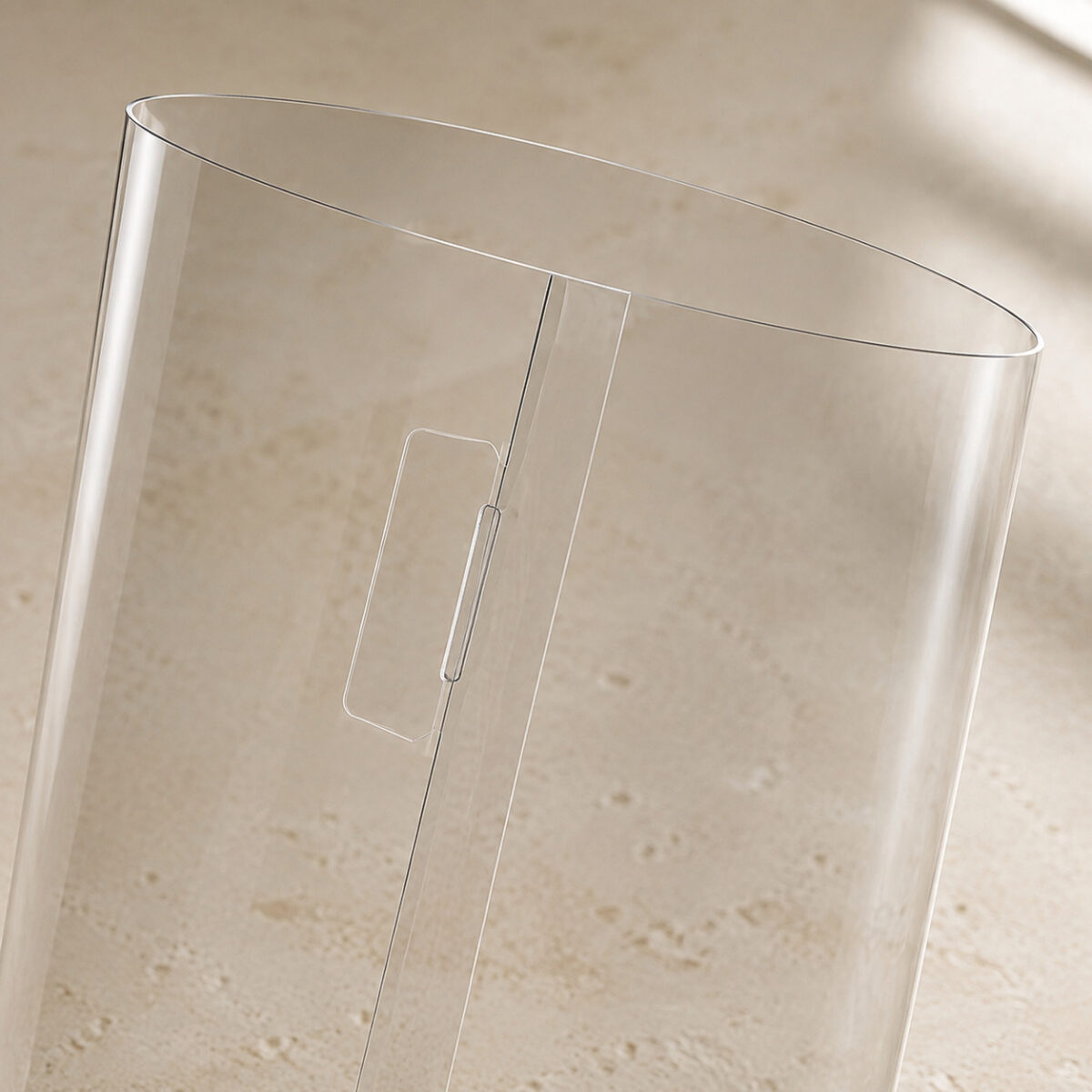Clear cylindrical cake-box sleeve detail showing the open top and rounded locking tongue beside the overlap seam