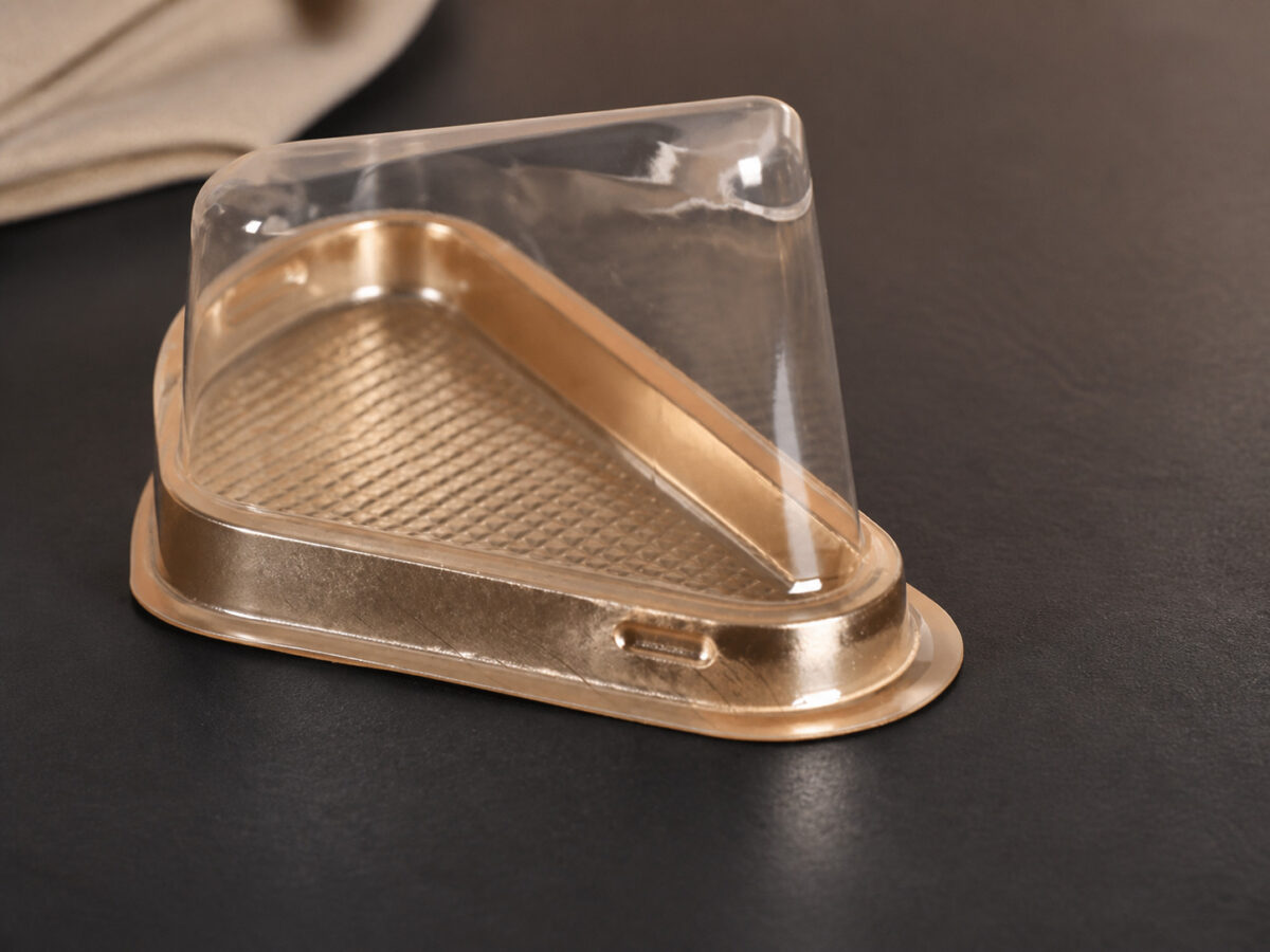 Close-up of a gold triangular cake slice tray with a clear lid and locking rim