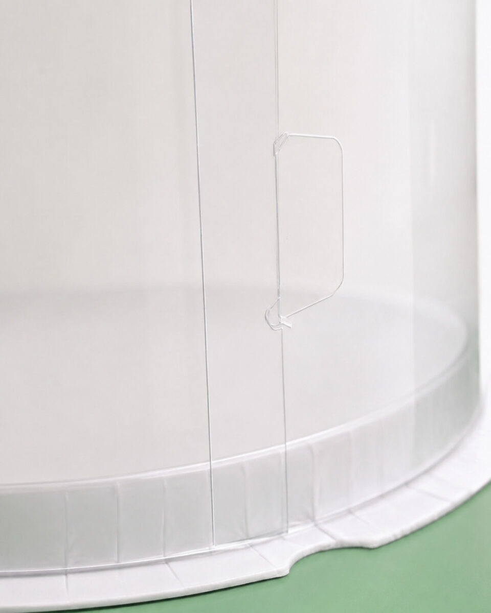 Close-up of the clear locking tab on a cylindrical cake box side seam