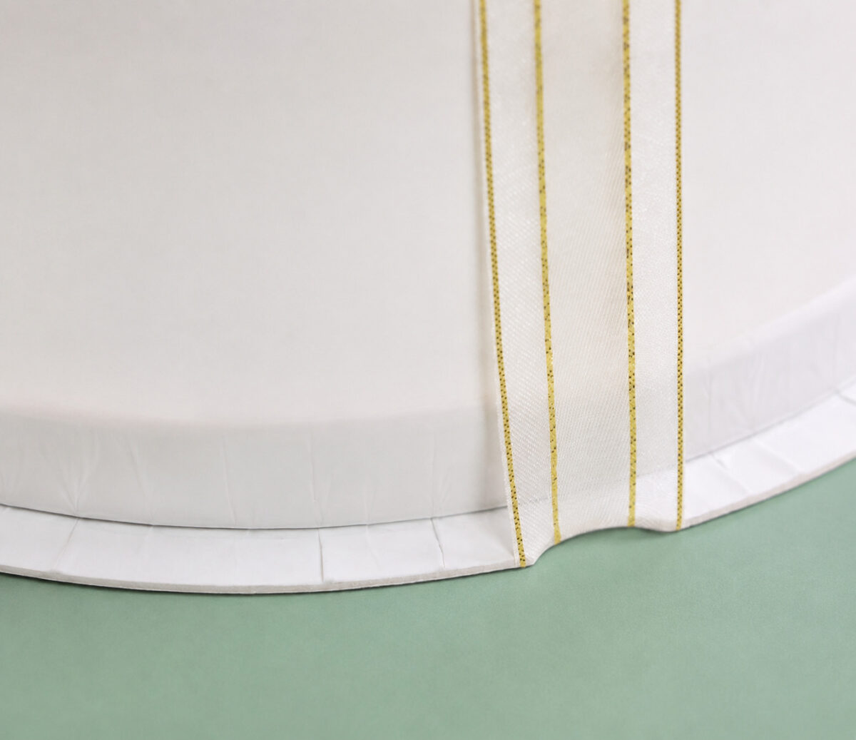 Ivory ribbon with four fine gold lines around a white round cake box base