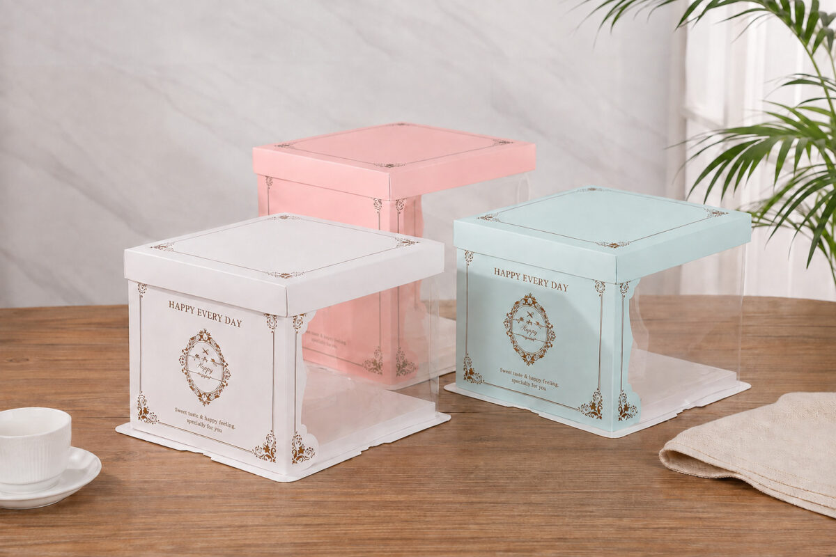 White, pink and mint window cake boxes with gold borders on a wooden table